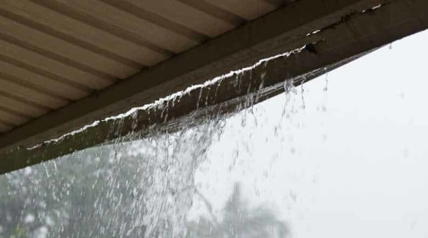 A picture of a house with visible water damage, mold, or foundation cracks caused by a leaky gutter