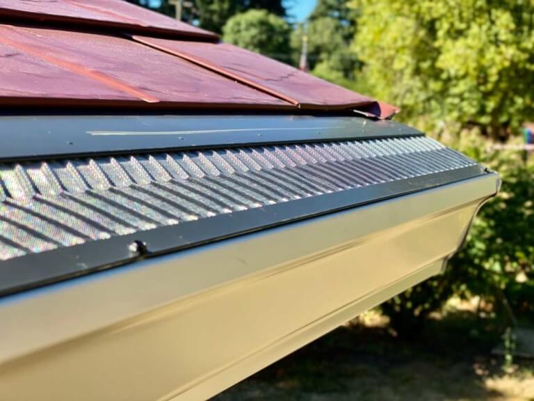A picture of a gutter guard on a gutter with leaves and debris on top of it