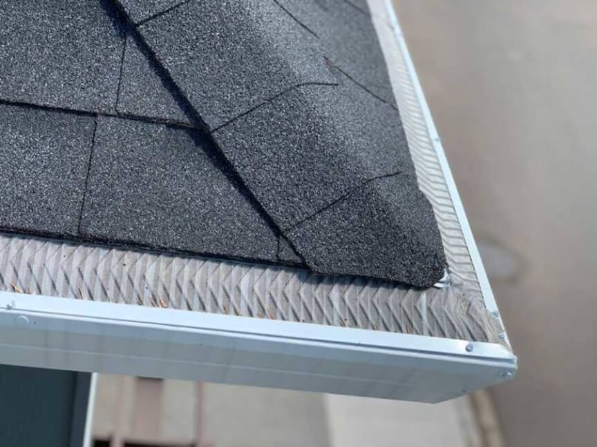 A close-up of a gutter guard with a few pieces of debris sitting on top of it