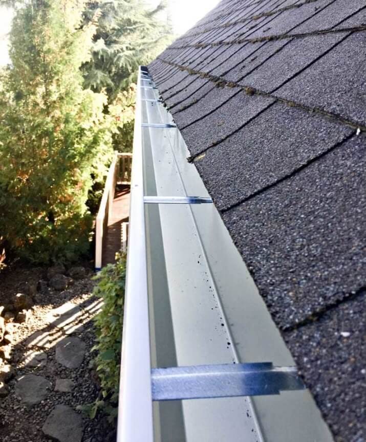 A long, continuous piece of seamless gutter being installed on a house