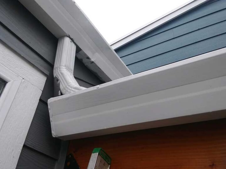 A diagram showing water flowing from a gutter and pooling near a house's foundation, causing a crack