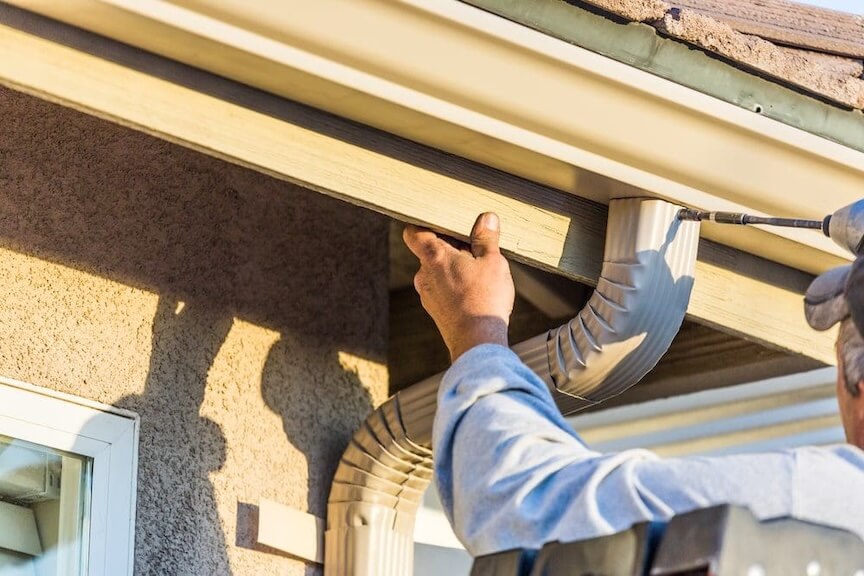 A team of professionals installing new seamless gutters on a house